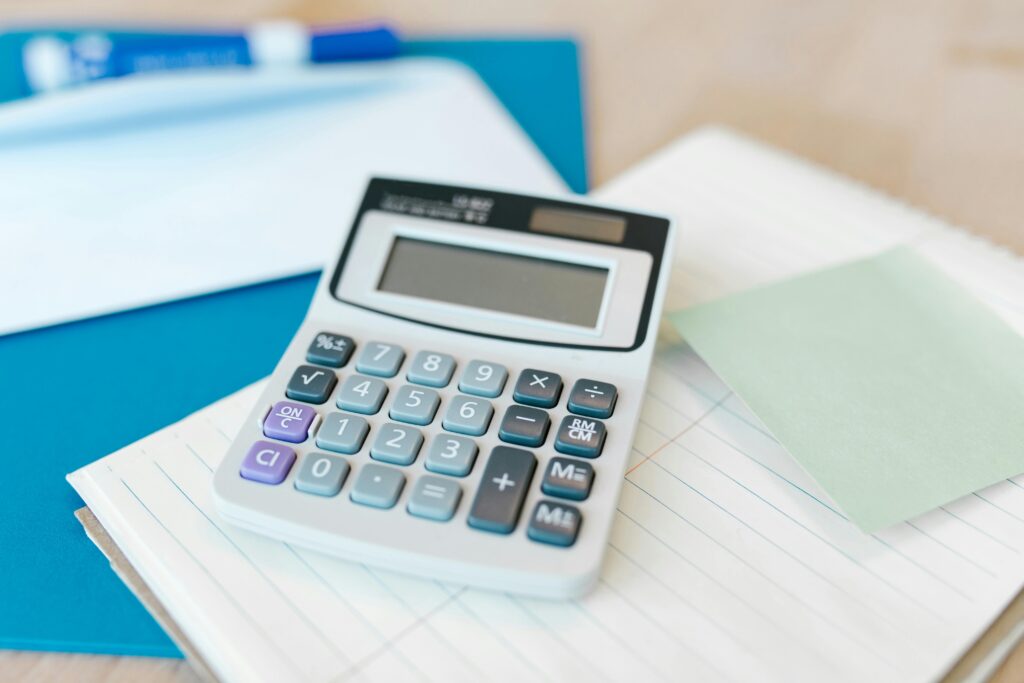 White calculator displaying blank screen sits on financial documents and papers, representing tax calculations and estate planning computations for inheritance tax planning in 2025