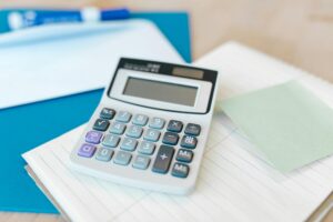 White calculator displaying blank screen sits on financial documents and papers, representing tax calculations and estate planning computations for inheritance tax planning in 2025
